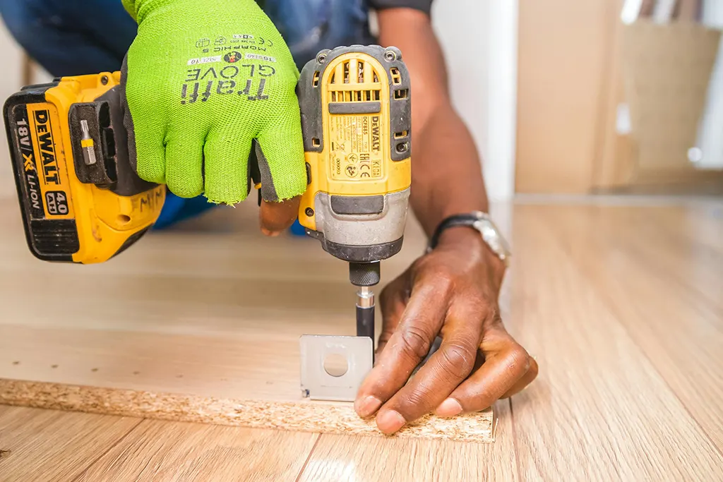 Hand working on wood with tool What Is Floor Refinishing and Why Does It Matter