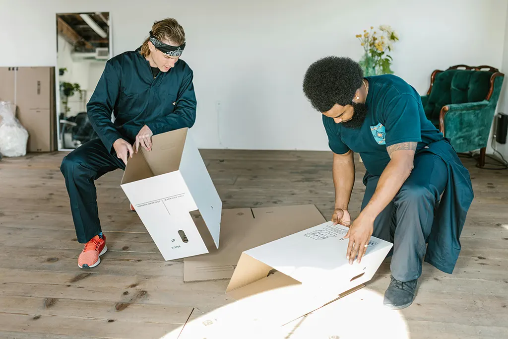 Two me in blue clohtes folding white boxes Move-Out Cleaning Magic a Game Changer for Home Transitions